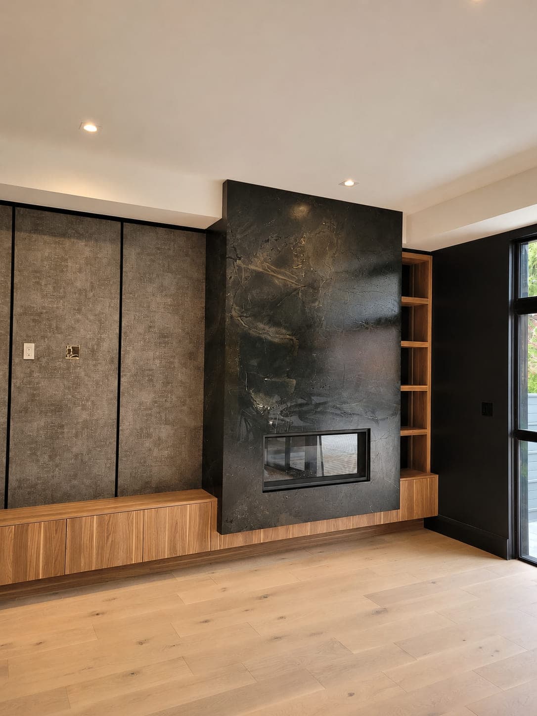 Same full-slab dark stone fireplace wall finished, with the fireplace insert installed and the room fully styled