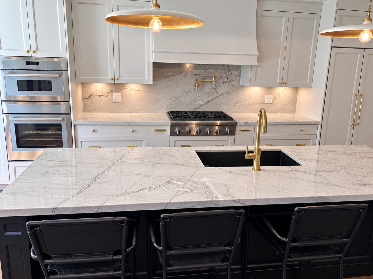 Sean Countertops interior perspective: a veined stone kitchen island with brass lighting