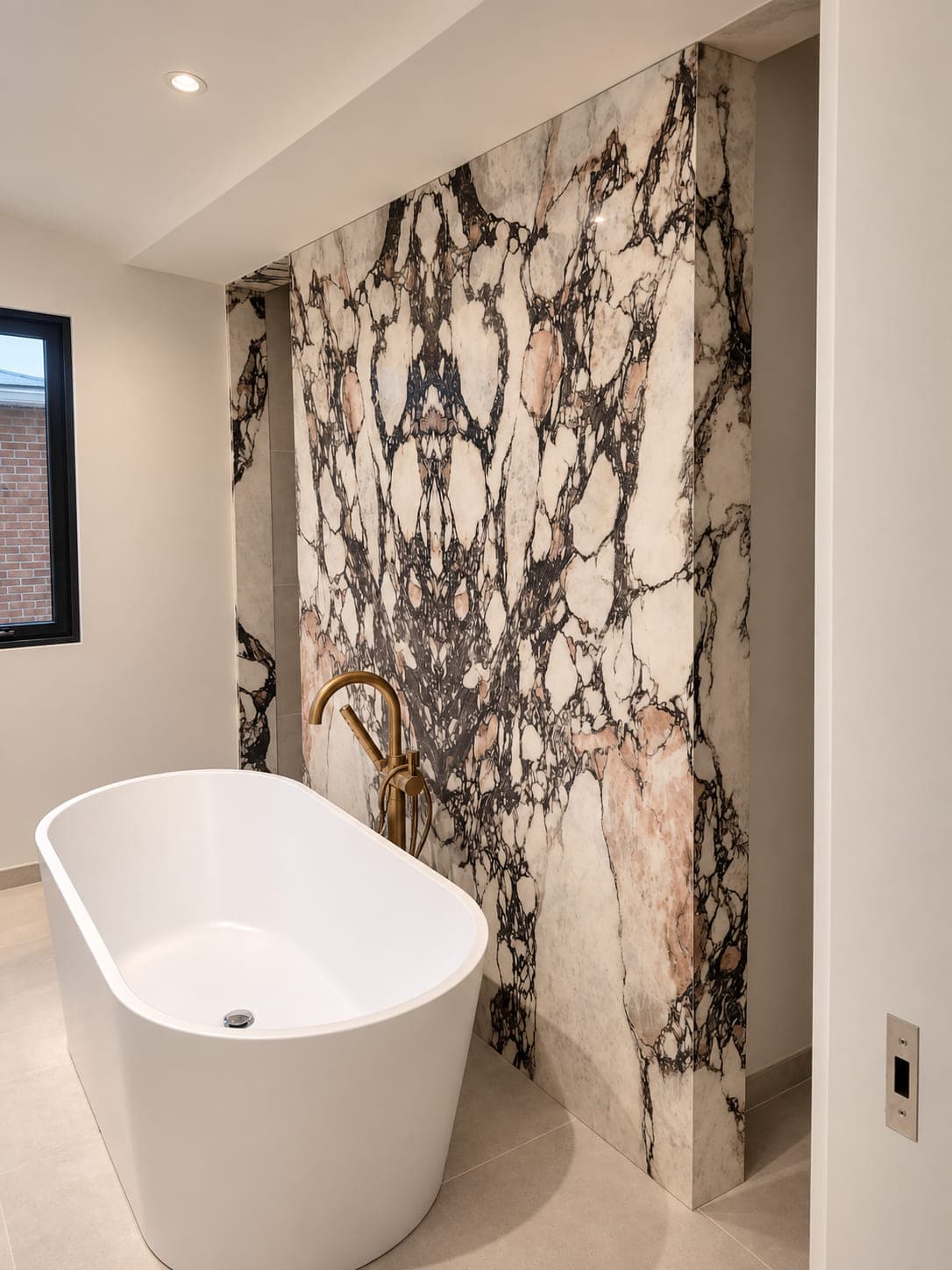 Patterned stone feature wall beside a freestanding bathtub