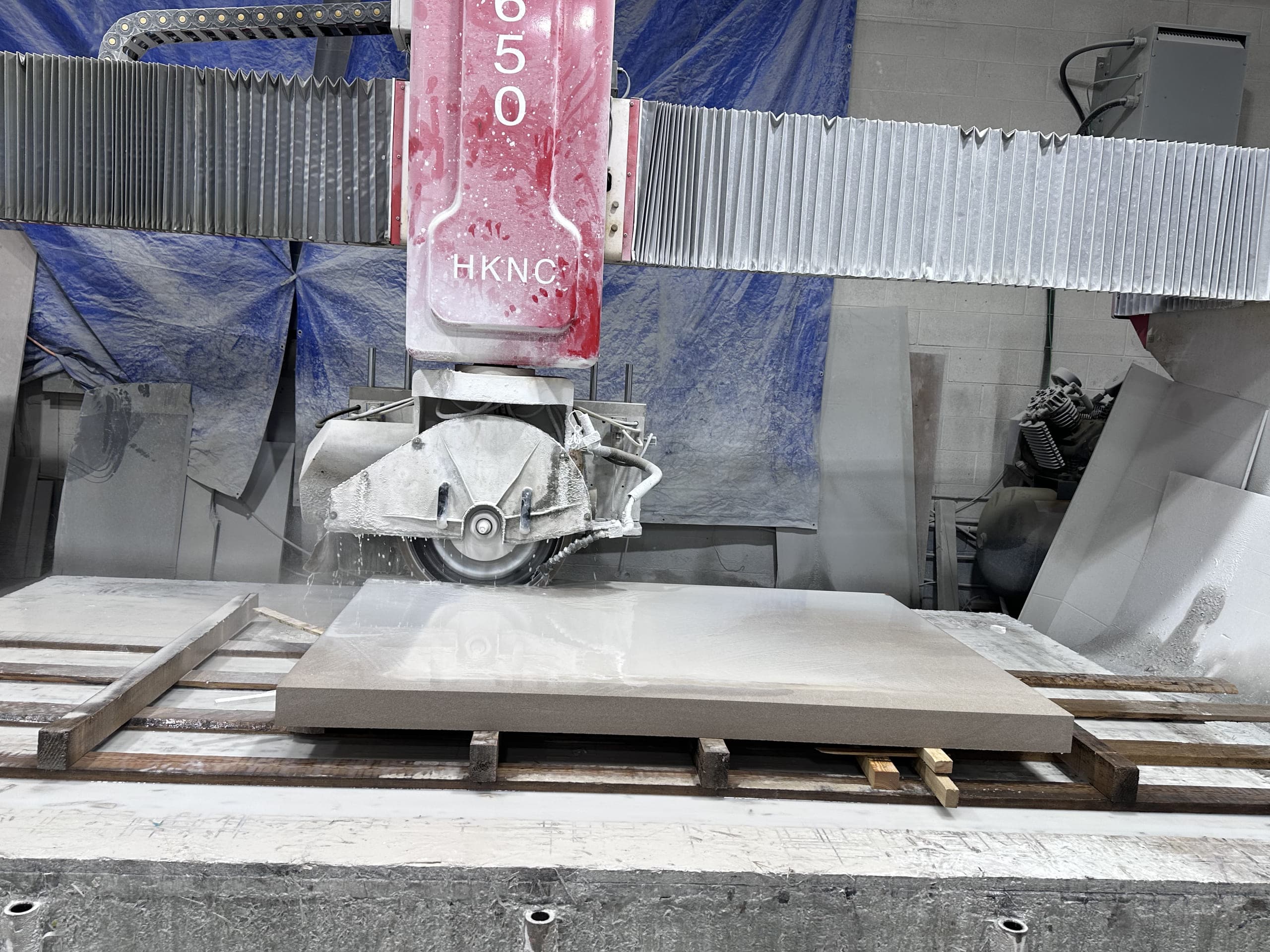 Stone slab positioned beneath a cutting head in the fabrication workshop