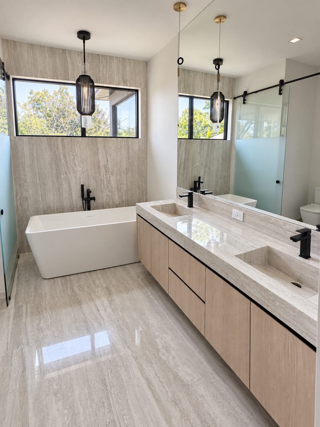 Pale stone double vanity with integrated basins and black fixtures