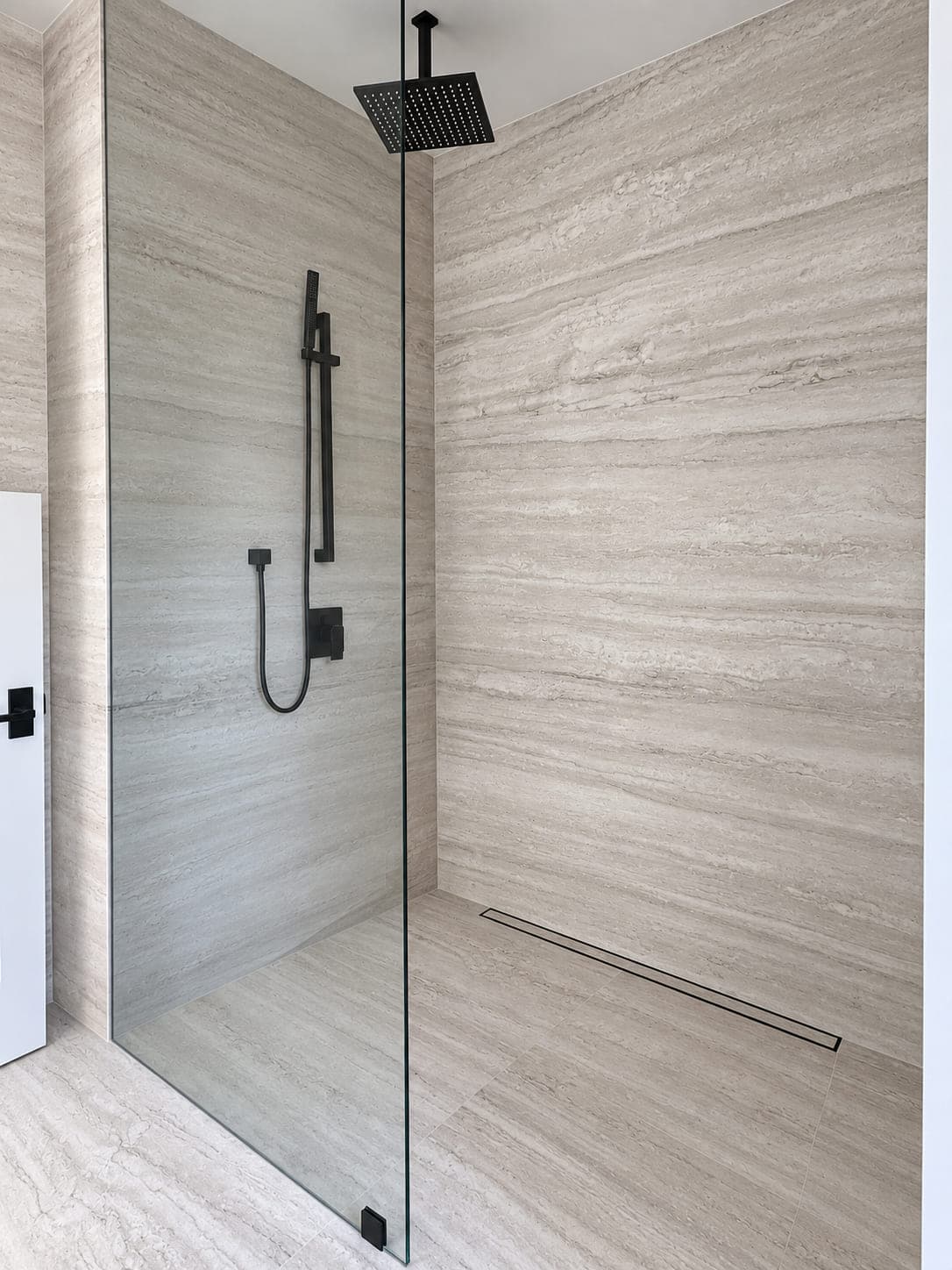 Pale stone shower walls and floor with a linear drain