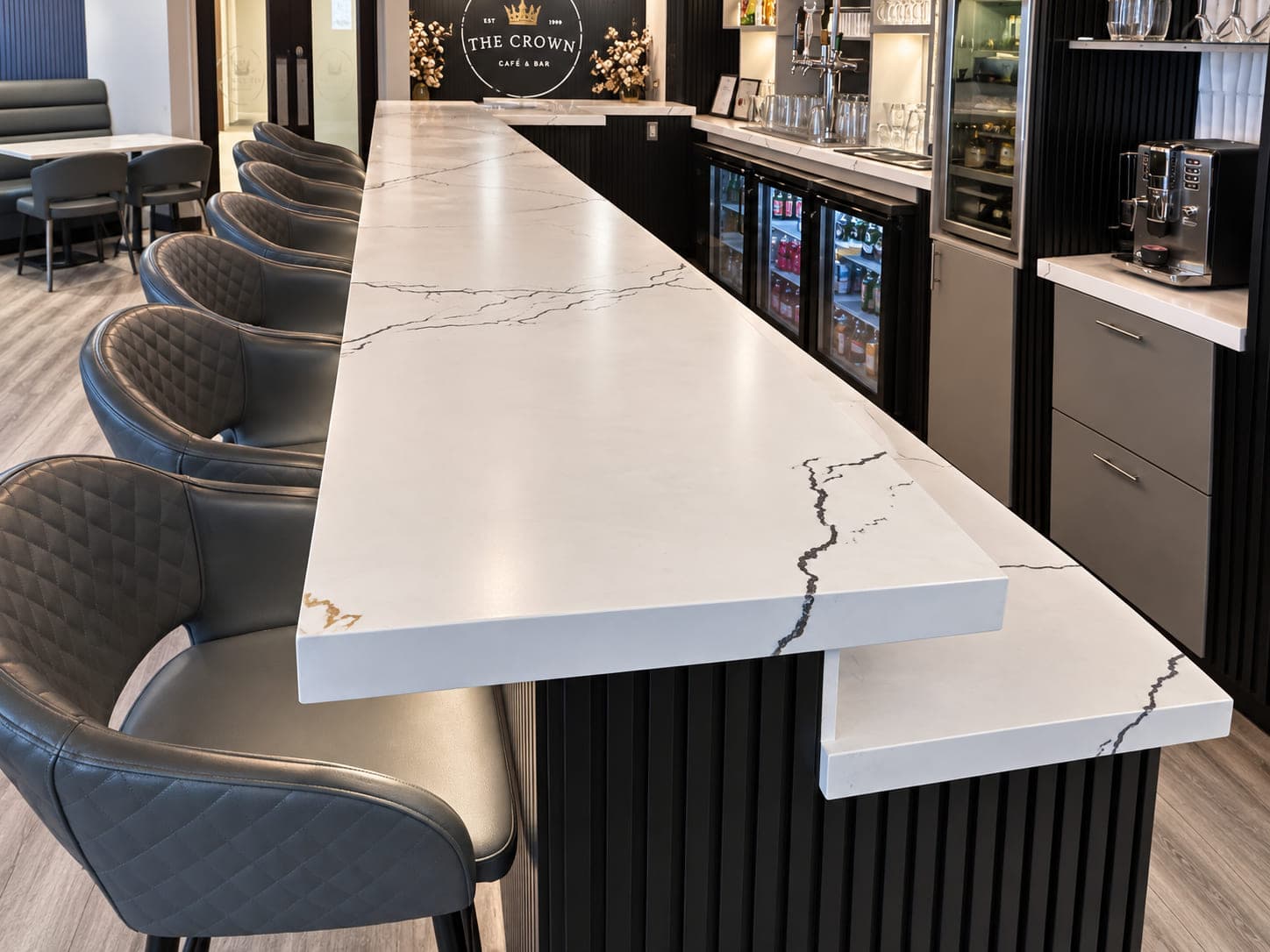 Veined stone bar countertop with upholstered stools and dark cabinetry